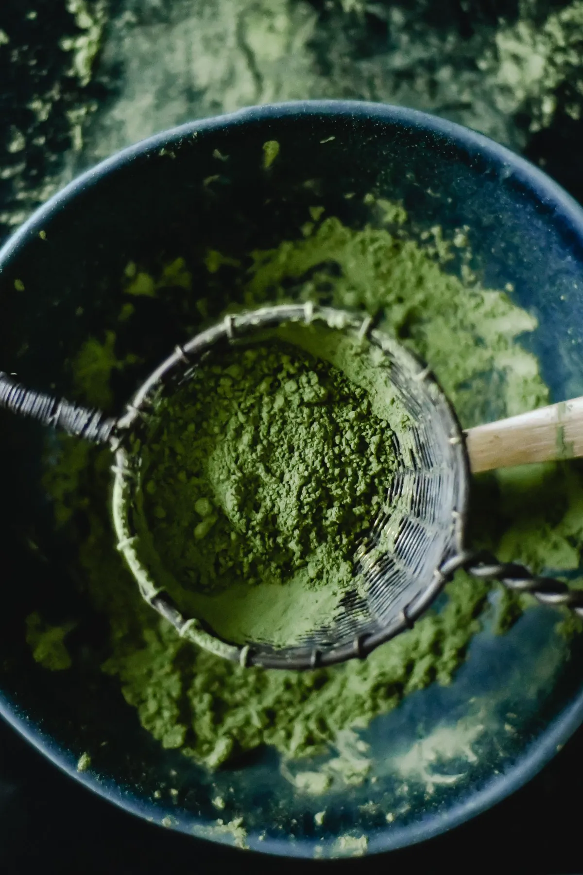 Té matcha en polvo tamizado sobre un colador visto desde arriba, con algún grumo