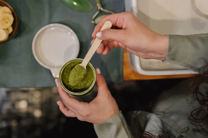 Cuchara de bambú tomando una porción de té matcha en polvo