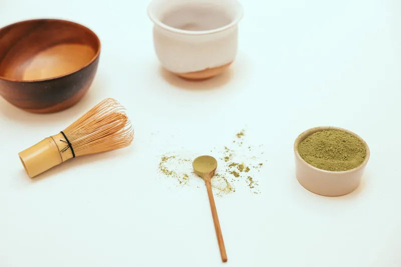 Polvo de matcha junto a un batidor chasen de bambú tradicional