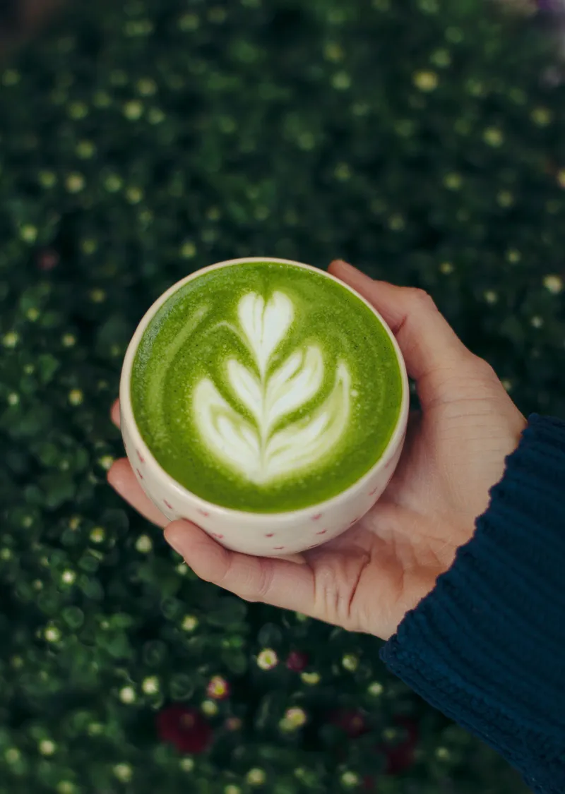 Matcha latte caliente con arte de hoja en la espuma